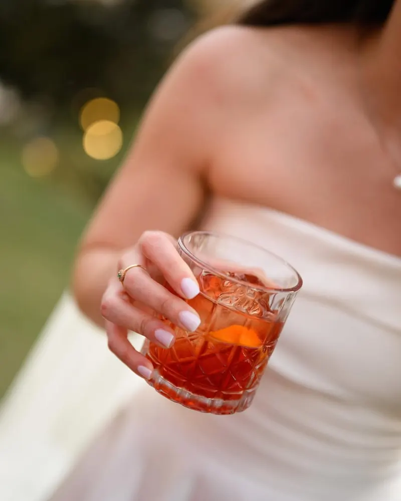 Convidada de casamento com coquetel na mão